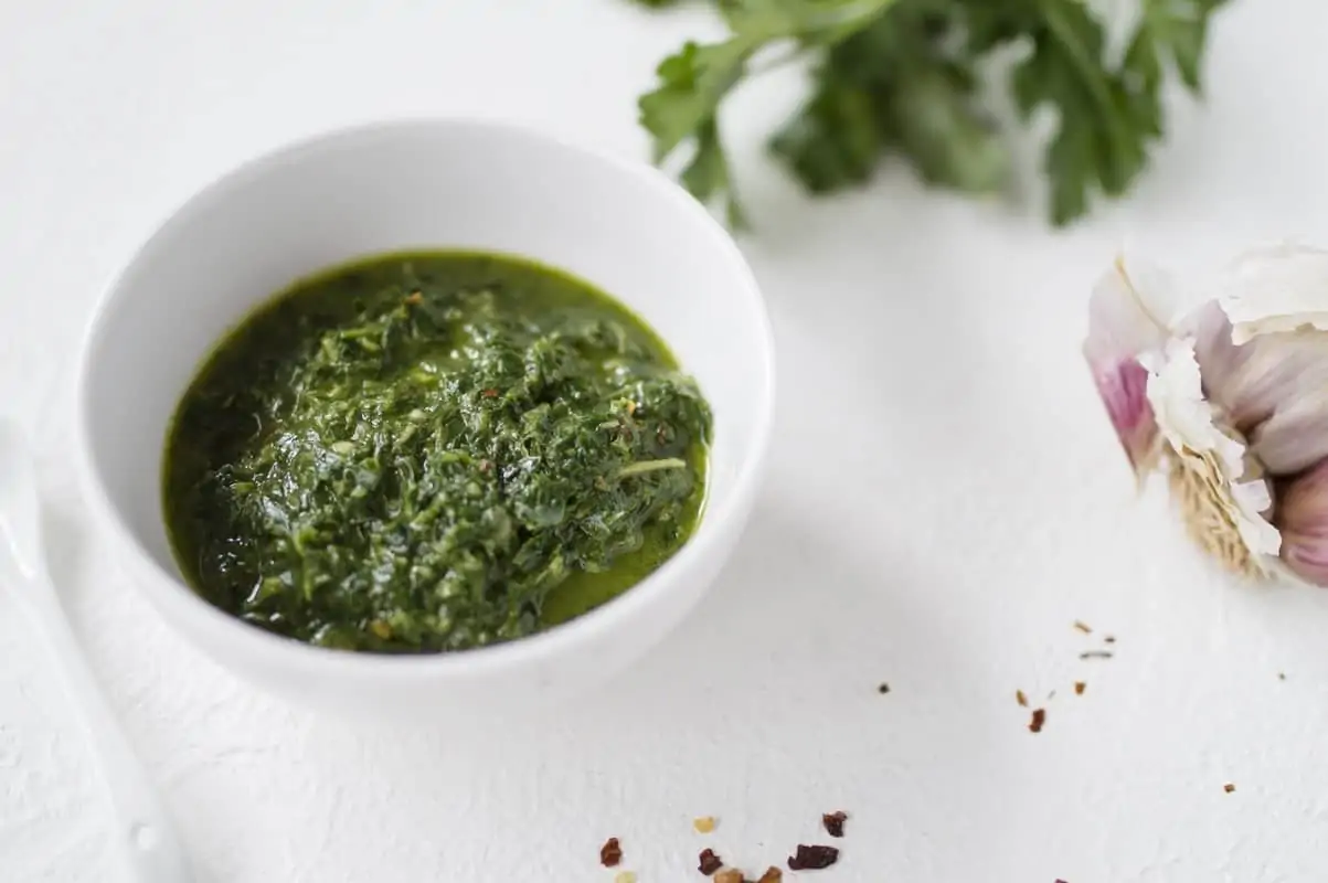 A dish of chimichurri - a green, herby Argentinian sauce