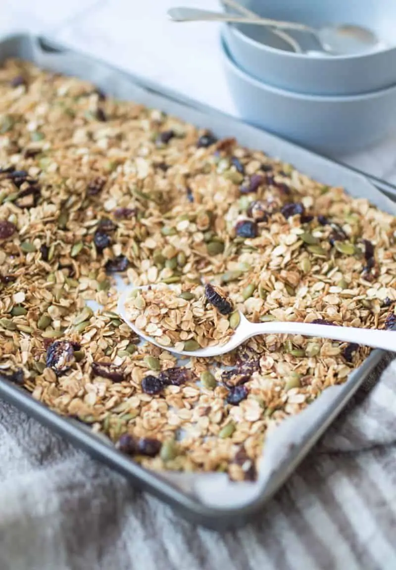 baking tray of nut free granola with white spoon resting on tray
