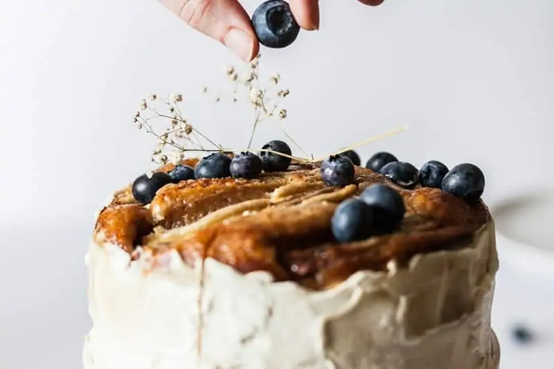 Hand putting blueberry on top of banana cake 