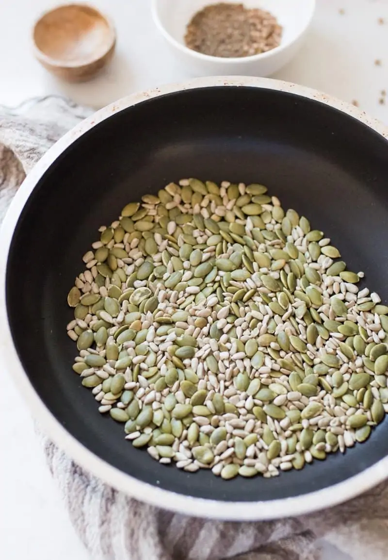 Fry pan with sunflower and pumpkin seeds in it that have been toasted to make nut free dukkah