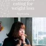 Woman in larger body with brown hair and black t-shirt sitting at a table. She is resting her chin on her hands with a downcast gaze, like she is being contemplative. Purple background with text overlay reads 'the low-down on intuitive eating for weight loss' feel good eating