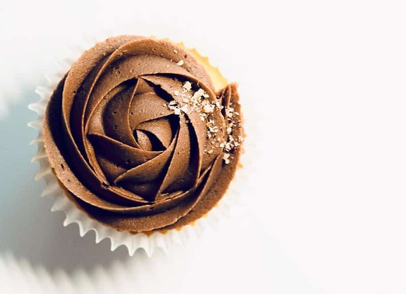 Single vanilla cupcake with swirls of chocolate frosting on a white background