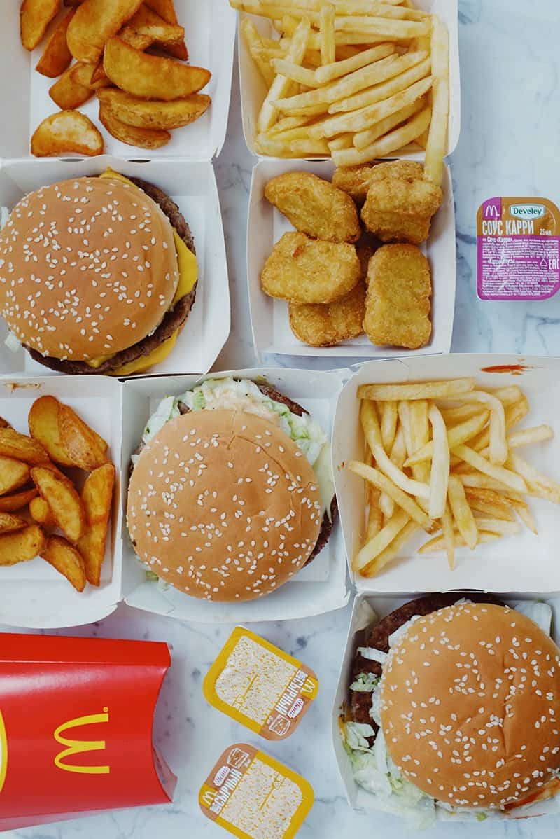 Flat lay of fast food. There are burgers, nuggets, fries, wedges and sauces