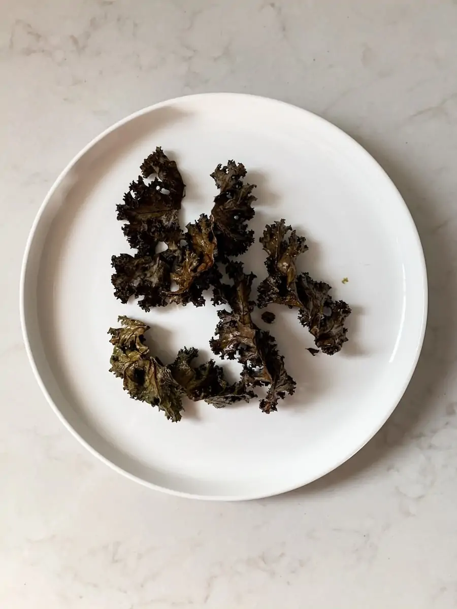A plate of burnt kale chips on a bench.