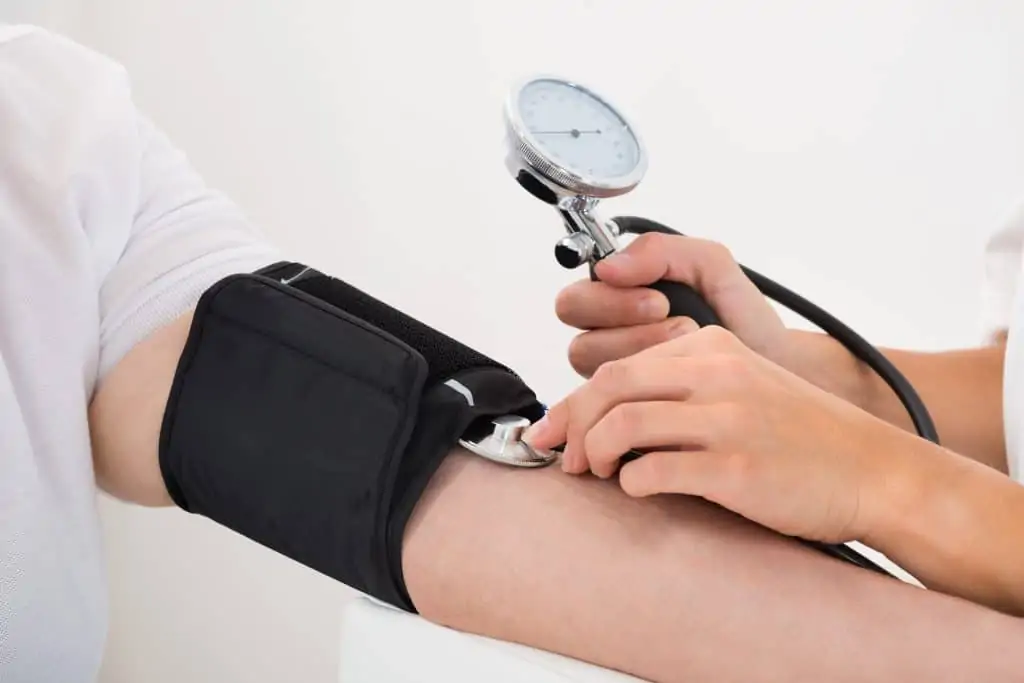 A close up of a health care provider taking a patient's blood pressure.