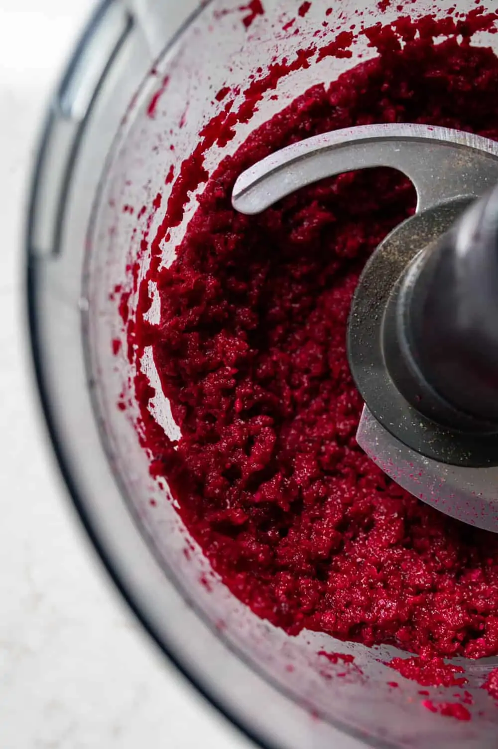 A close up of a food processor bowl showing the blitzed roasted beetroot dip