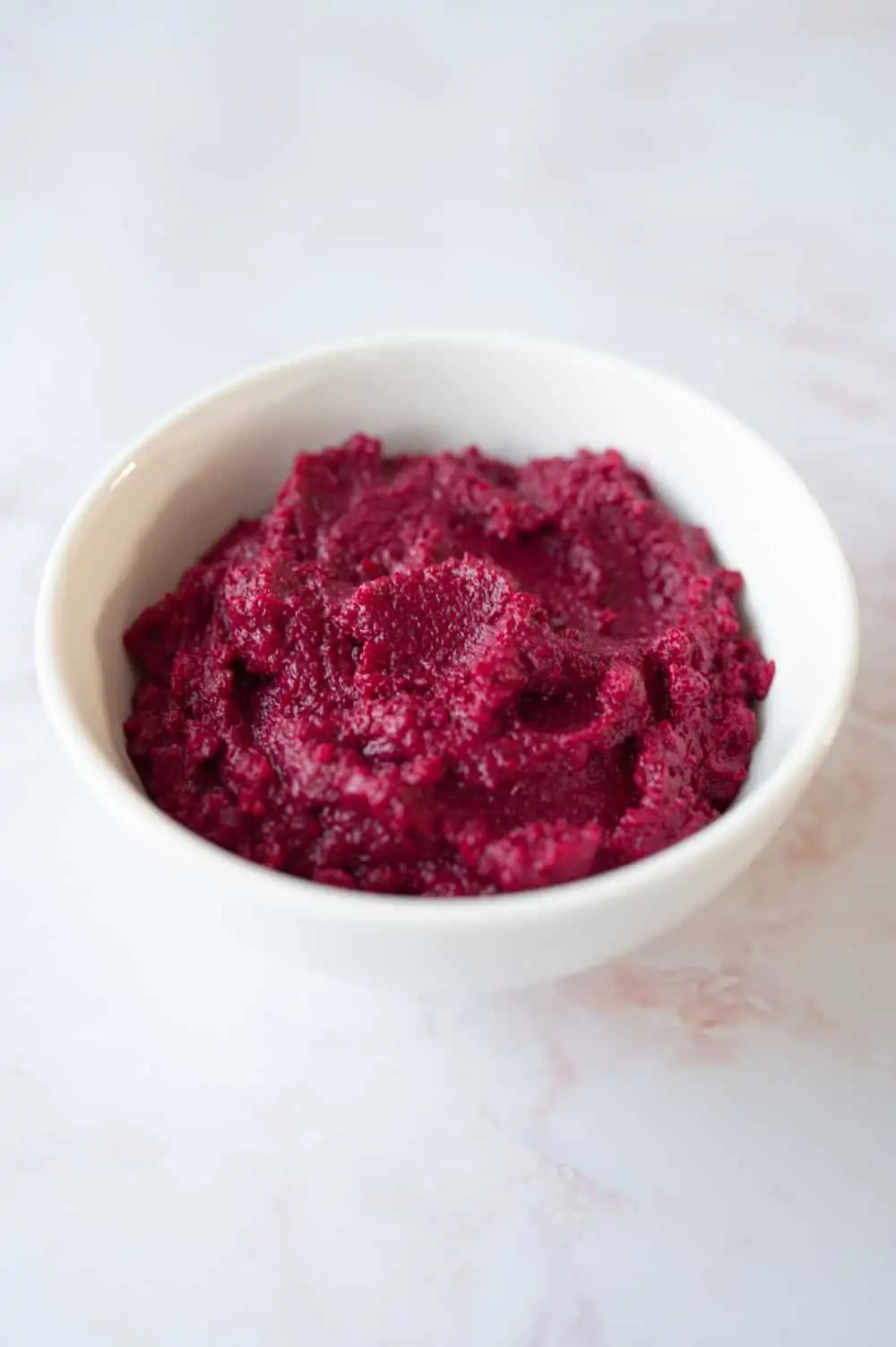 A small white bowl filled with roasted beetroot dip